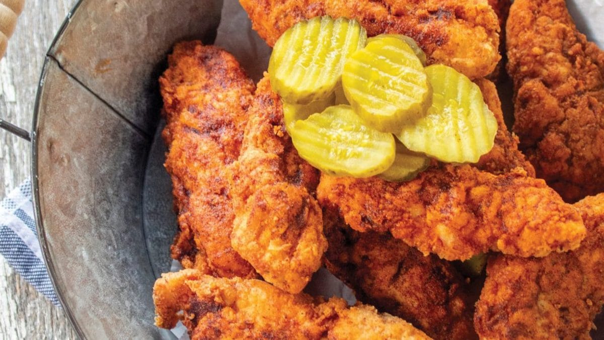 Chicken tenders with pickles on top.