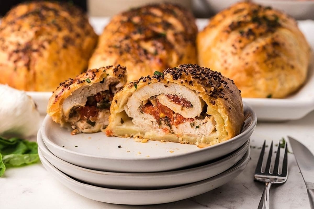 Stuffed chicken breast on a stack of plates.