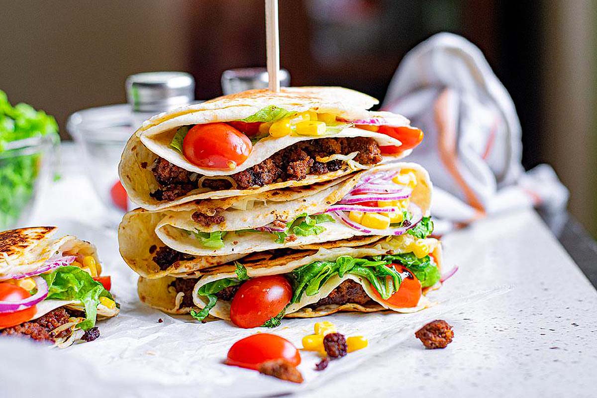 A tortilla folded into quarters with beef and vegetables in it.
