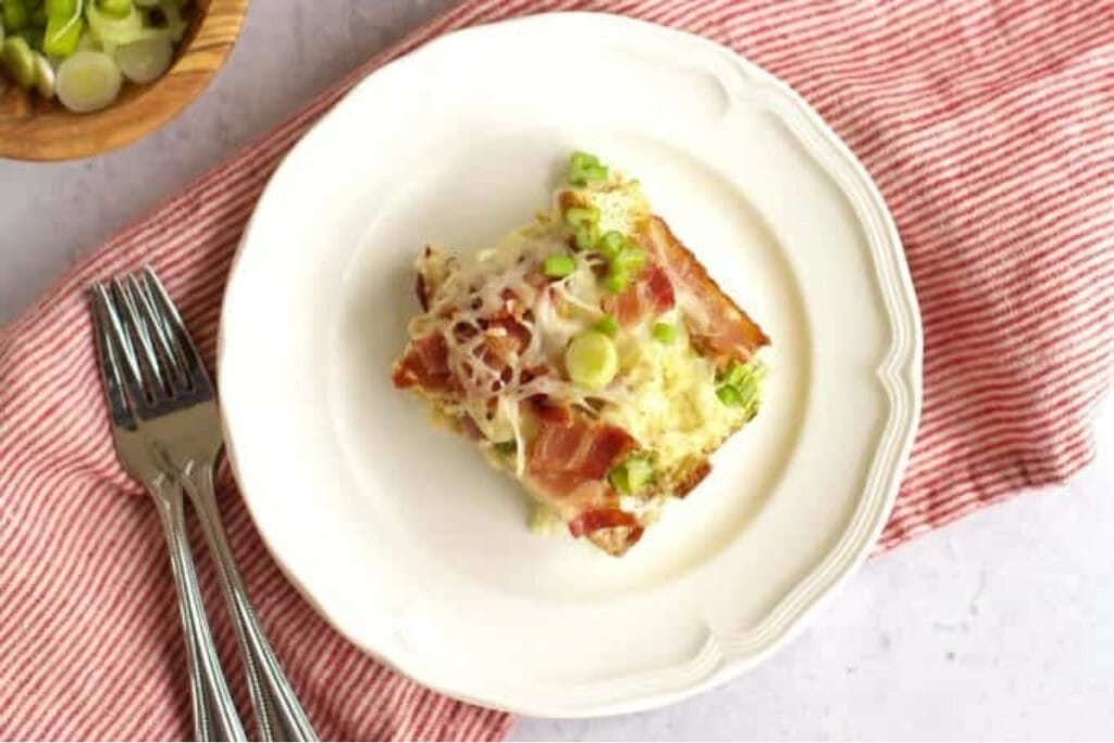 Breakfast casserole slice on a plate with a red towel.