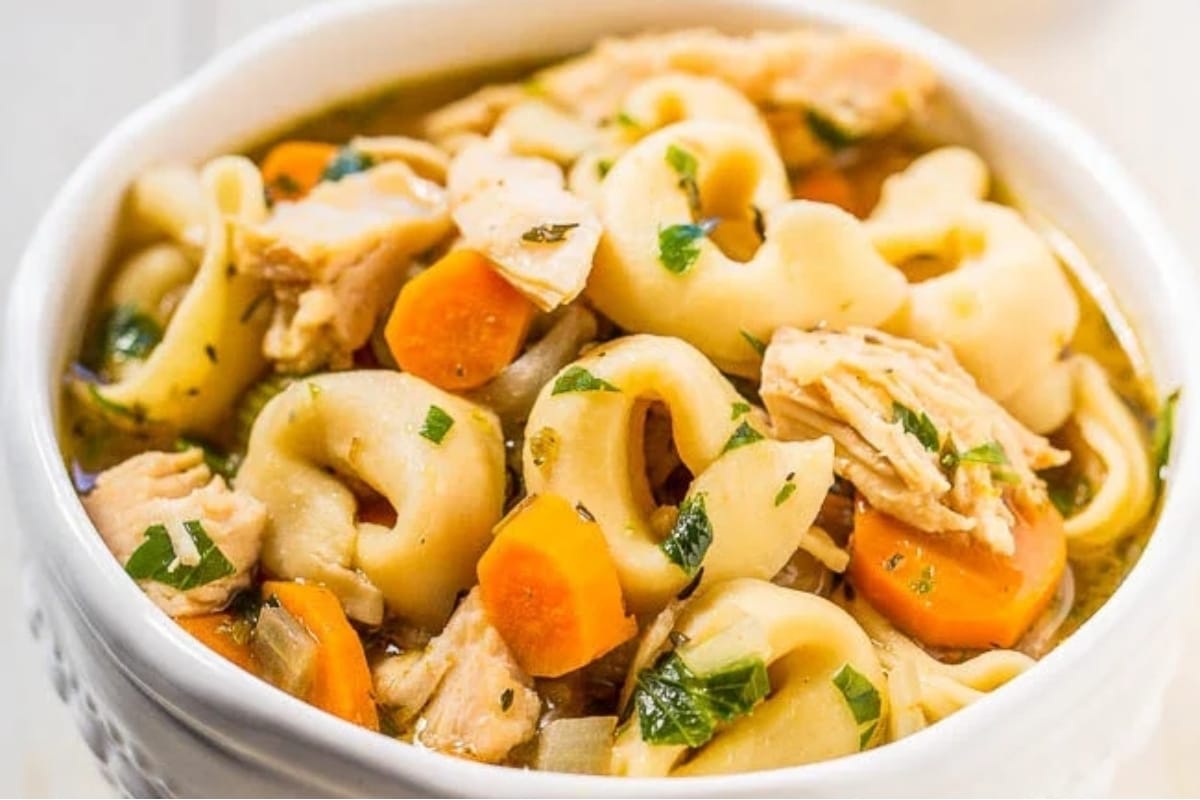 Delightful chicken tortellini soup served in a white bowl.