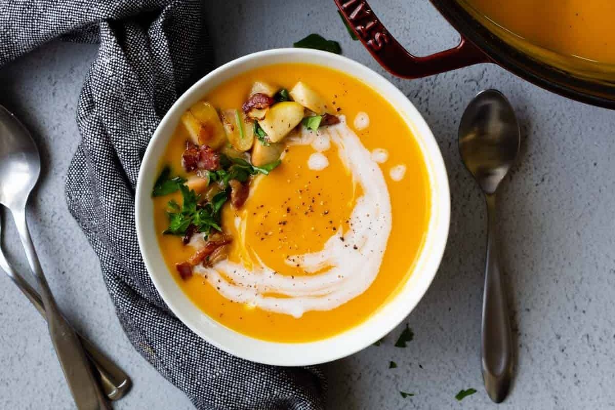 butternut squash soup with cream on top on blue background