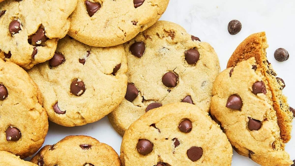 A scrumptious pile of chocolate chip cookies, fresh out of the oven and begging to be devoured. One lucky cookie already bears the mark of a delightful bite.