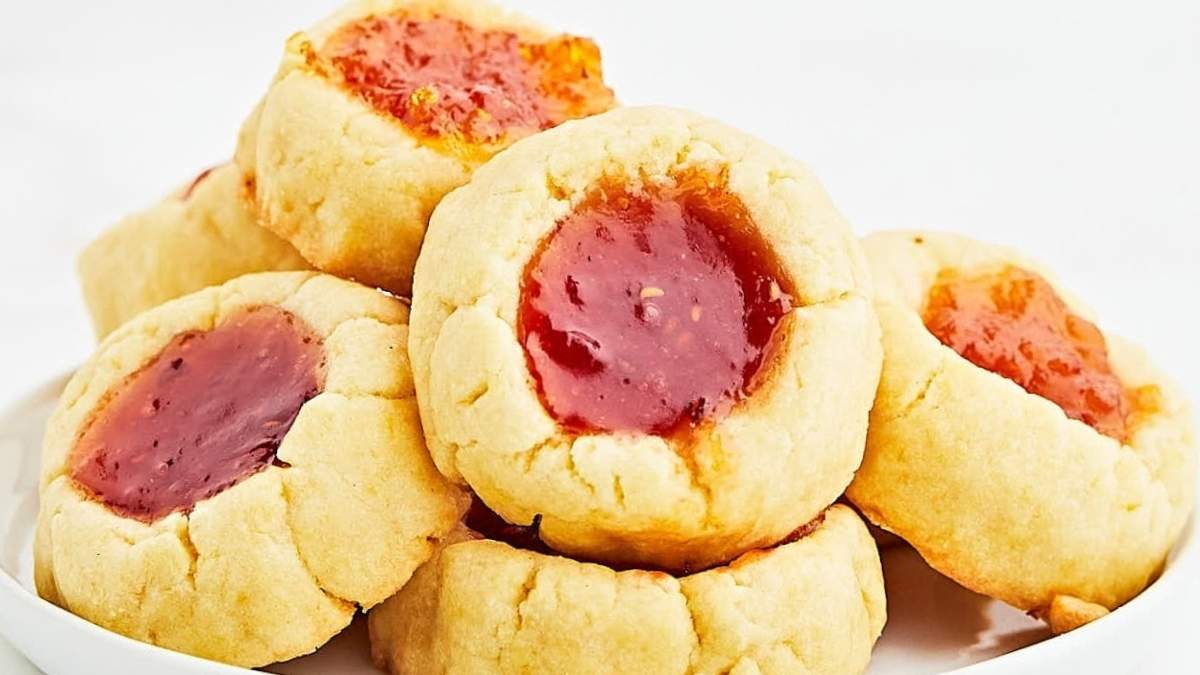 A plate of cookies with jam on top, surrounded by a collection of homemade cookie recipes.