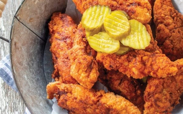 Chicken tenders with pickles on top.