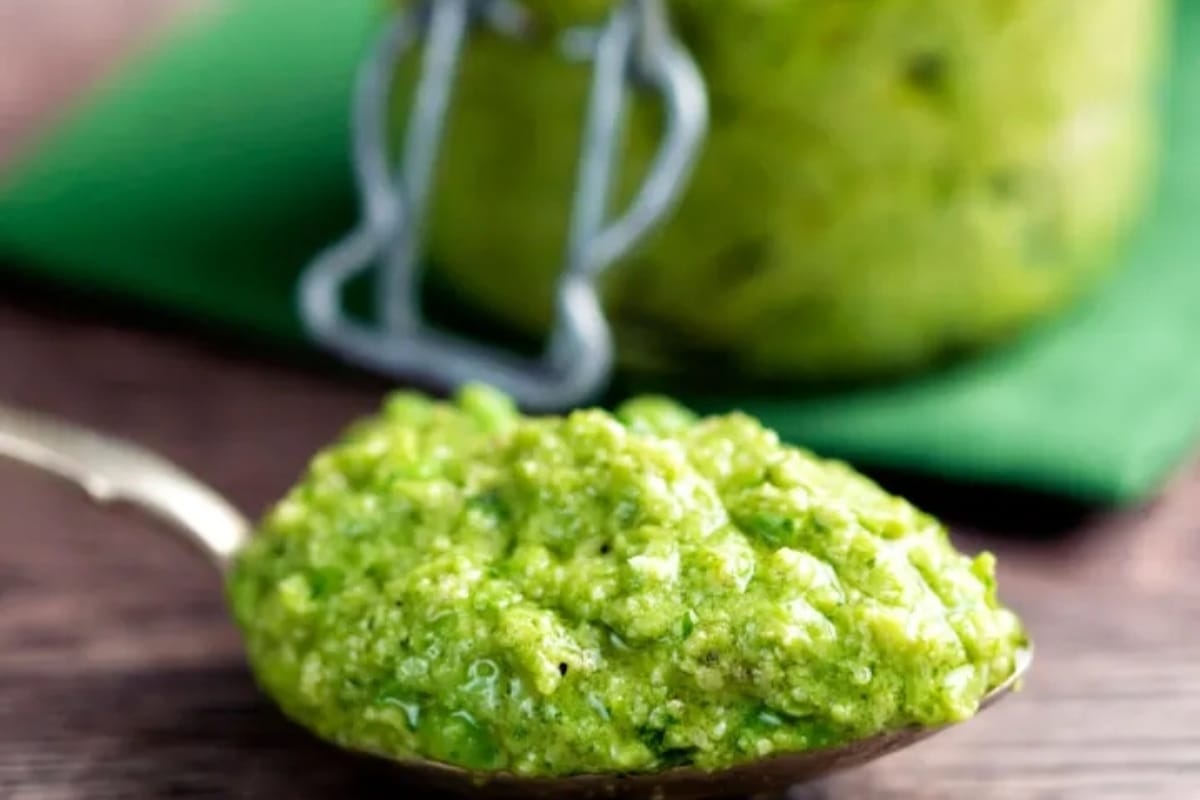 Pea pesto in a jar with a spoon.