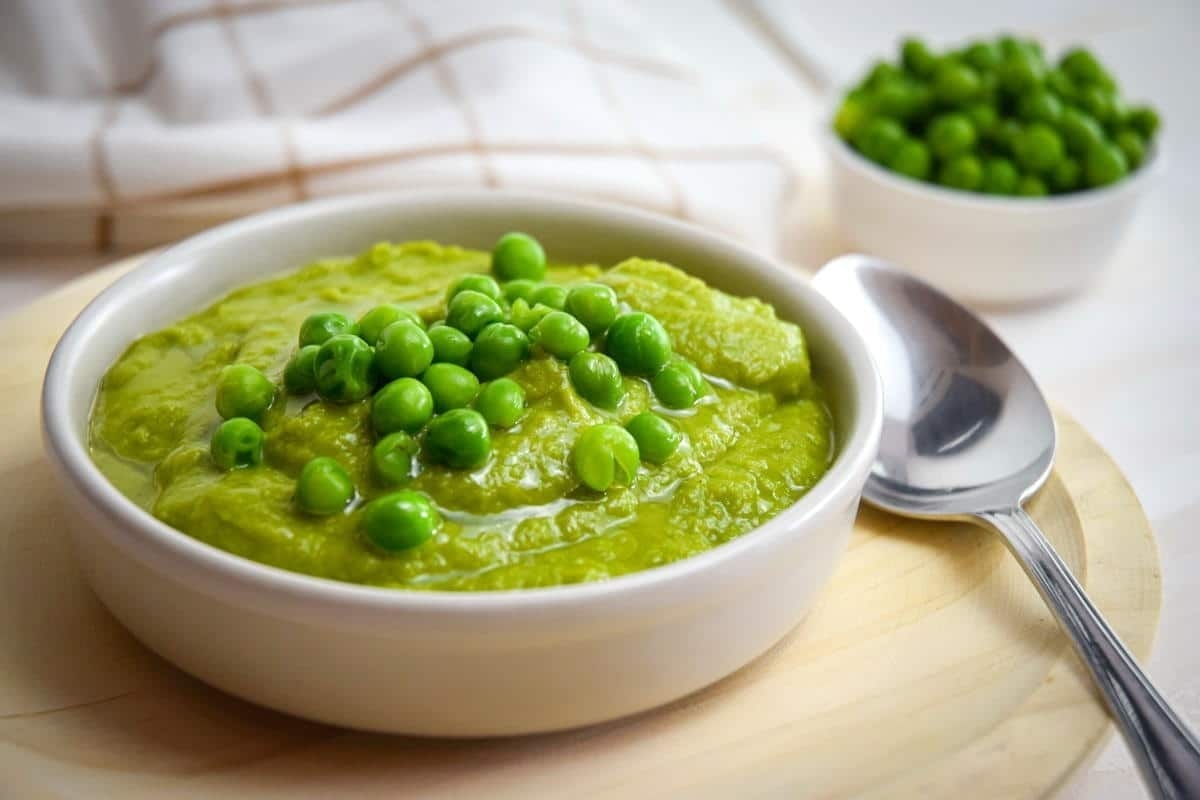 A bowl of green pea puree with a spoon.