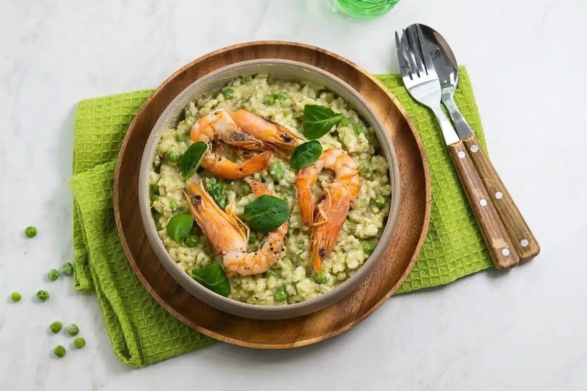 A bowl of risotto with shrimp and peas.