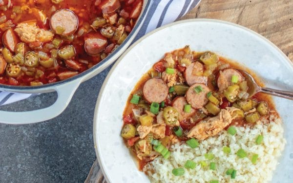 Gumbo with sausage on rice in a white bowl.