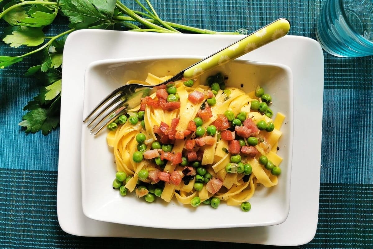 A plate of pasta with peas and bacon.