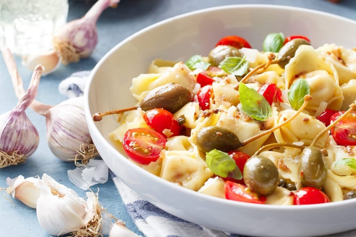 A delicious tortellini recipe featuring tomatoes, olives, and garlic.