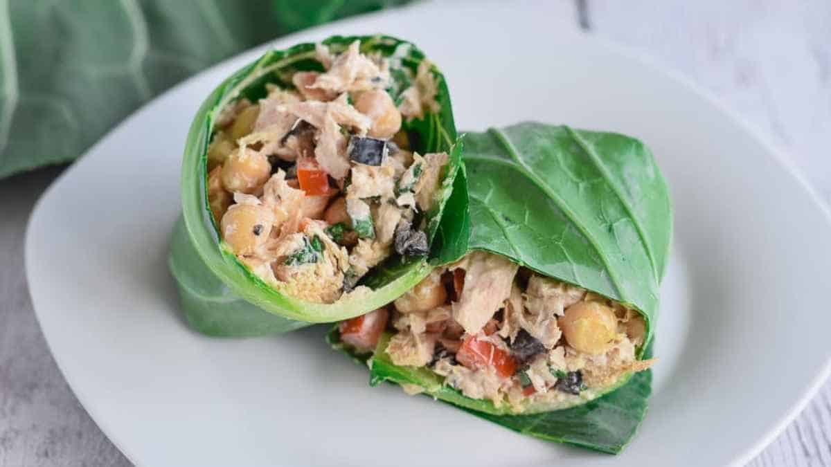 Chicken salad wrapped in a green leaf on a white plate.
