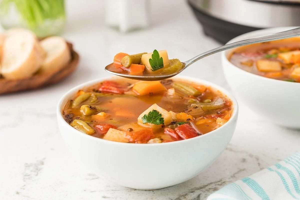 Two bowls of soup filled with frozen mixed vegetables in front of an instant pot.