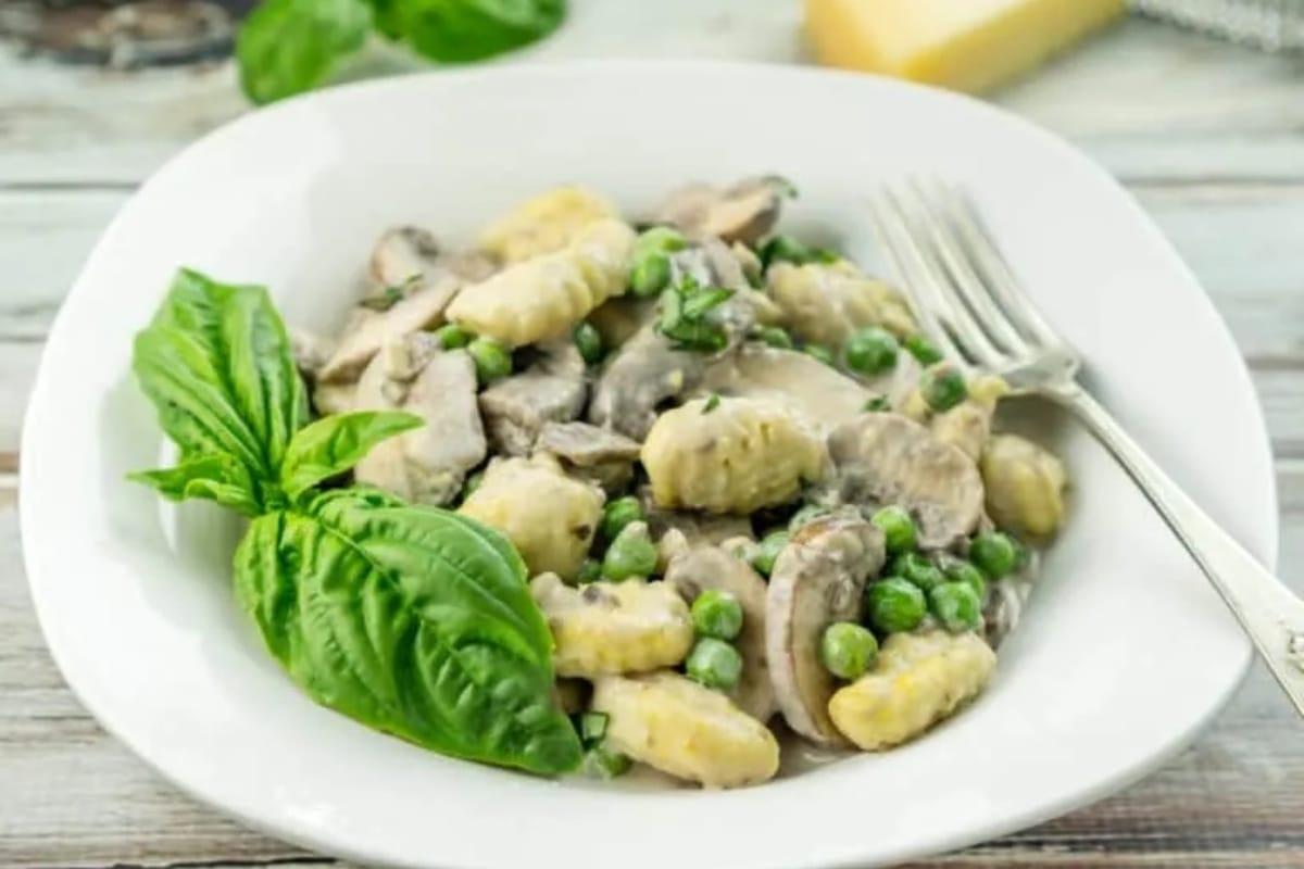 Mushrooms and peas in a white bowl with a fork.