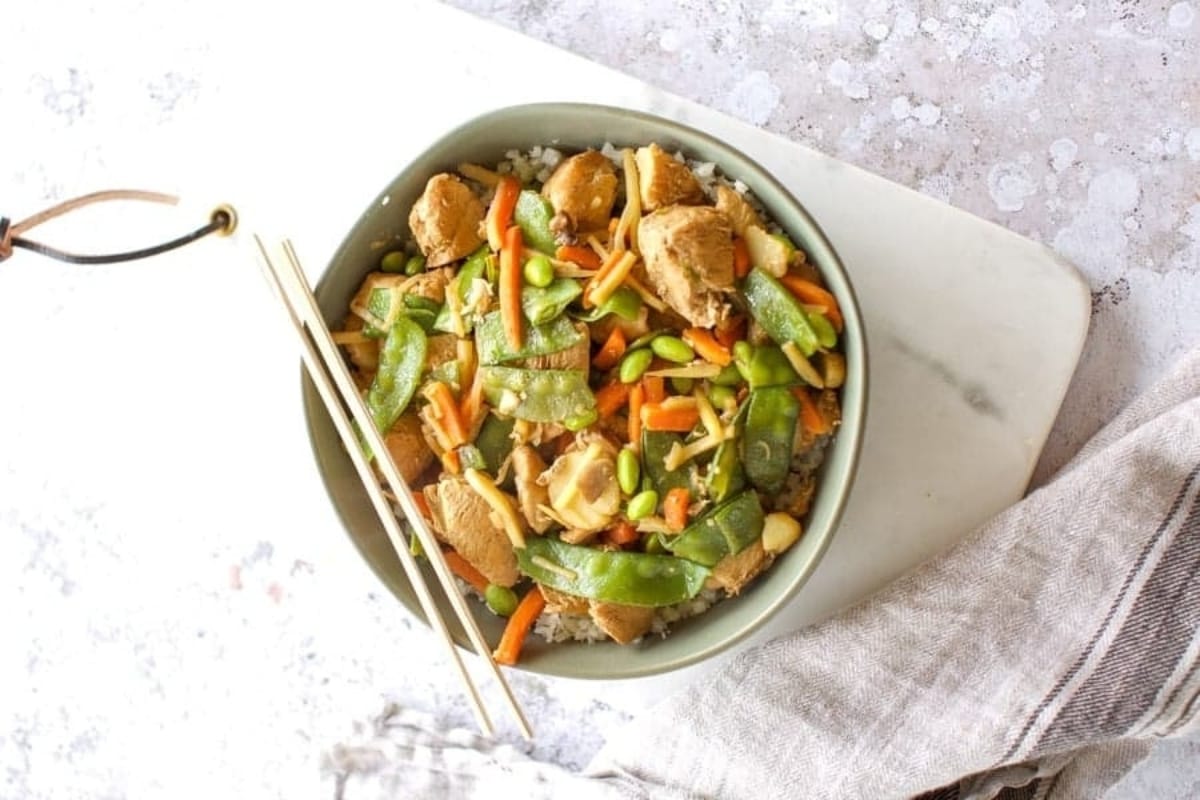 A savory chicken stir fry recipe served in a bowl, paired with the convenience of chopsticks for an authentic dining experience. This flavorful dish incorporates frozen mixed vegetables to add a colorful and nutritious twist