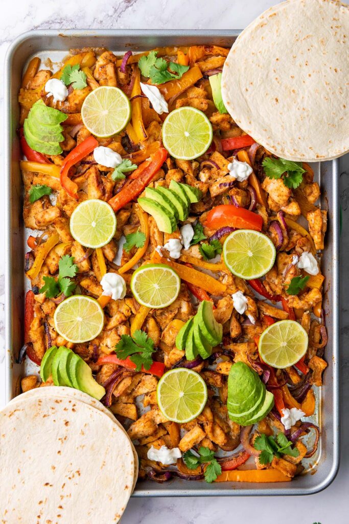 Two chicken fajitas with sliced limes on top.