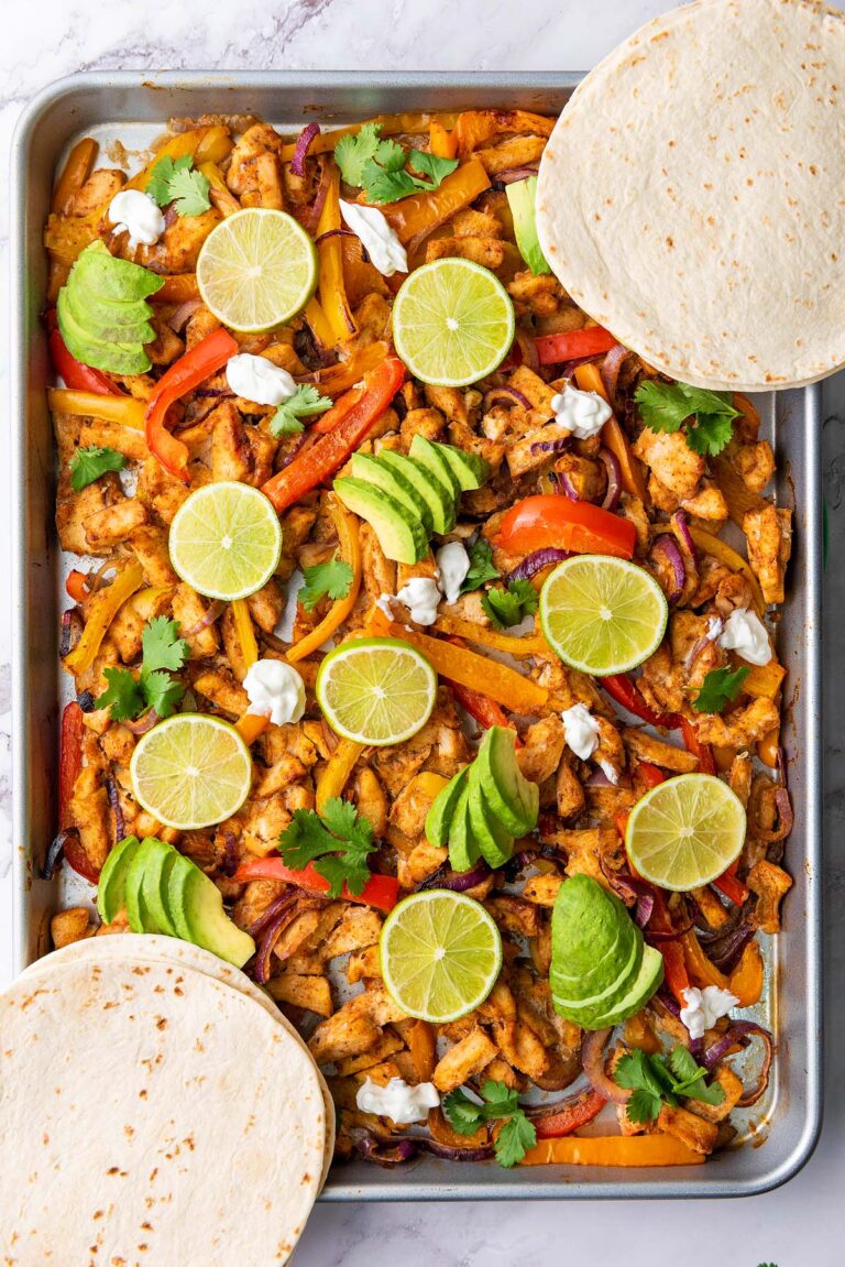 Two chicken fajitas with sliced limes on top.