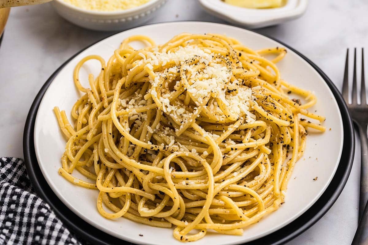 Cacio e pepe on a plate with a fork lifting a bite.