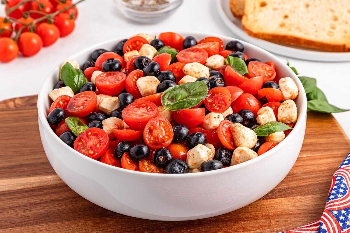 Blueberry tomato caprese salad in a white bowl.