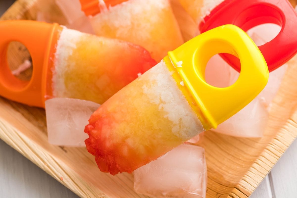 Tropical popsicles on ice, along with coconut halves and a halved pineapple.
